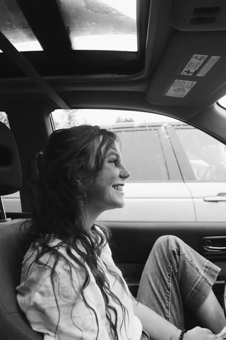 A smiling passenger sitting inside a taxi with a sunroof